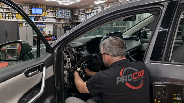 Pro Car technician installing a remote starter under the dashboard