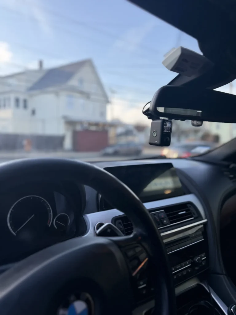 BMW dashboard from the driver's seat, with the dash cam tucked behind the rearview mirror